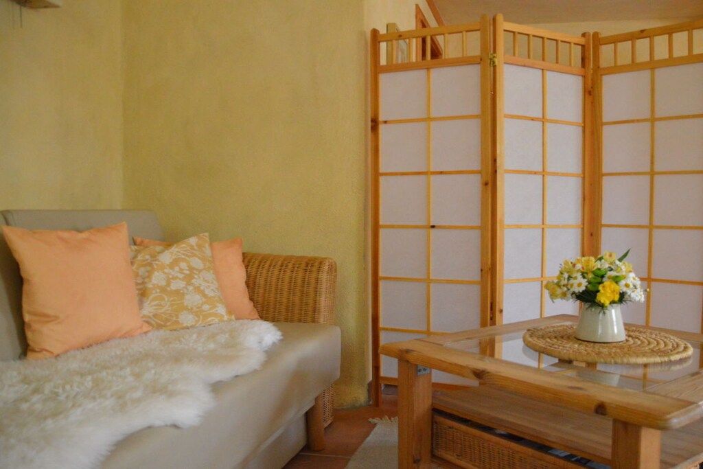 Una stanza con un divano, un pannello in legno e un tavolino con un vaso di fiori.