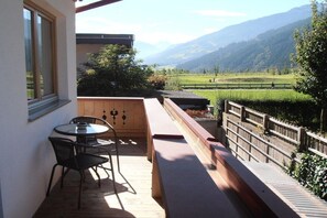 A balcony with a wooden table and chairs, overlooking a mountainous landscape. - Top 2 in the Alpin house (Uderns)