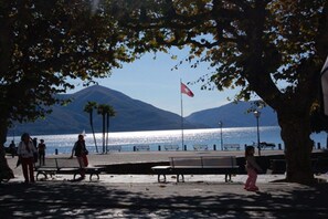 Une promenade en bord de mer, avec des bancs, un drapeau et une montagne en arrière-plan.