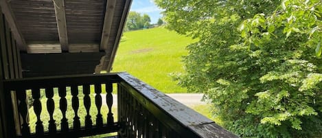 Un balcón de madera con vistas a un campo verde y árboles.