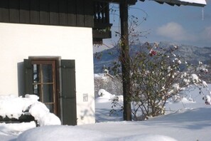 Ein Gebäude mit verschneitem Eingang und einem Blick auf verschneite Berge im Hintergrund.
