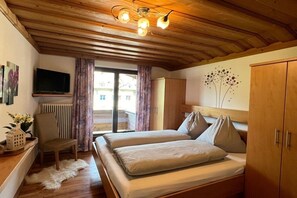 A bedroom with a bed, a chair, a television, and a view of the outside. - Lady's Mantle - Apartment (St. Johann Pongau)