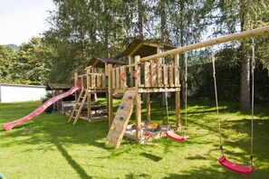A wooden playground structure with a slide, climbing wall, and swings. - Lady's Mantle - Apartment (St. Johann Pongau)