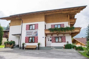 A traditional chalet-style building with a wooden facade, a sign advertising a restaurant, and a bench outside. - Lady's Mantle - Apartment (St. Johann Pongau)