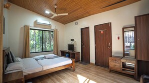 Un dormitorio con techo de madera, una cama, un escritorio, un televisor y dos puertas.