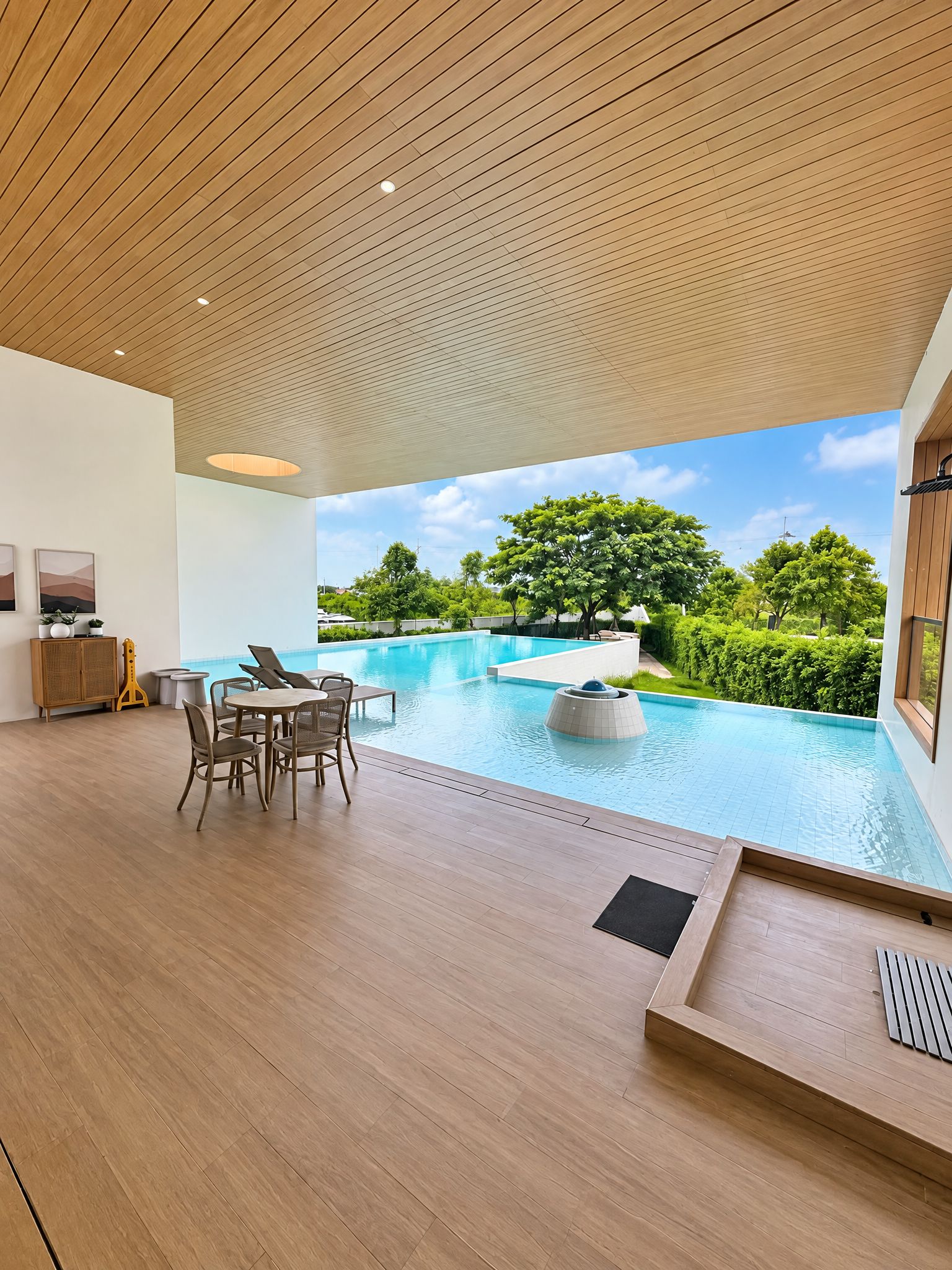 Un área interior de piscina moderna con techo de madera, una zona de estar con sillas y una mesa, y vistas a un jardín ajardinado con árboles.