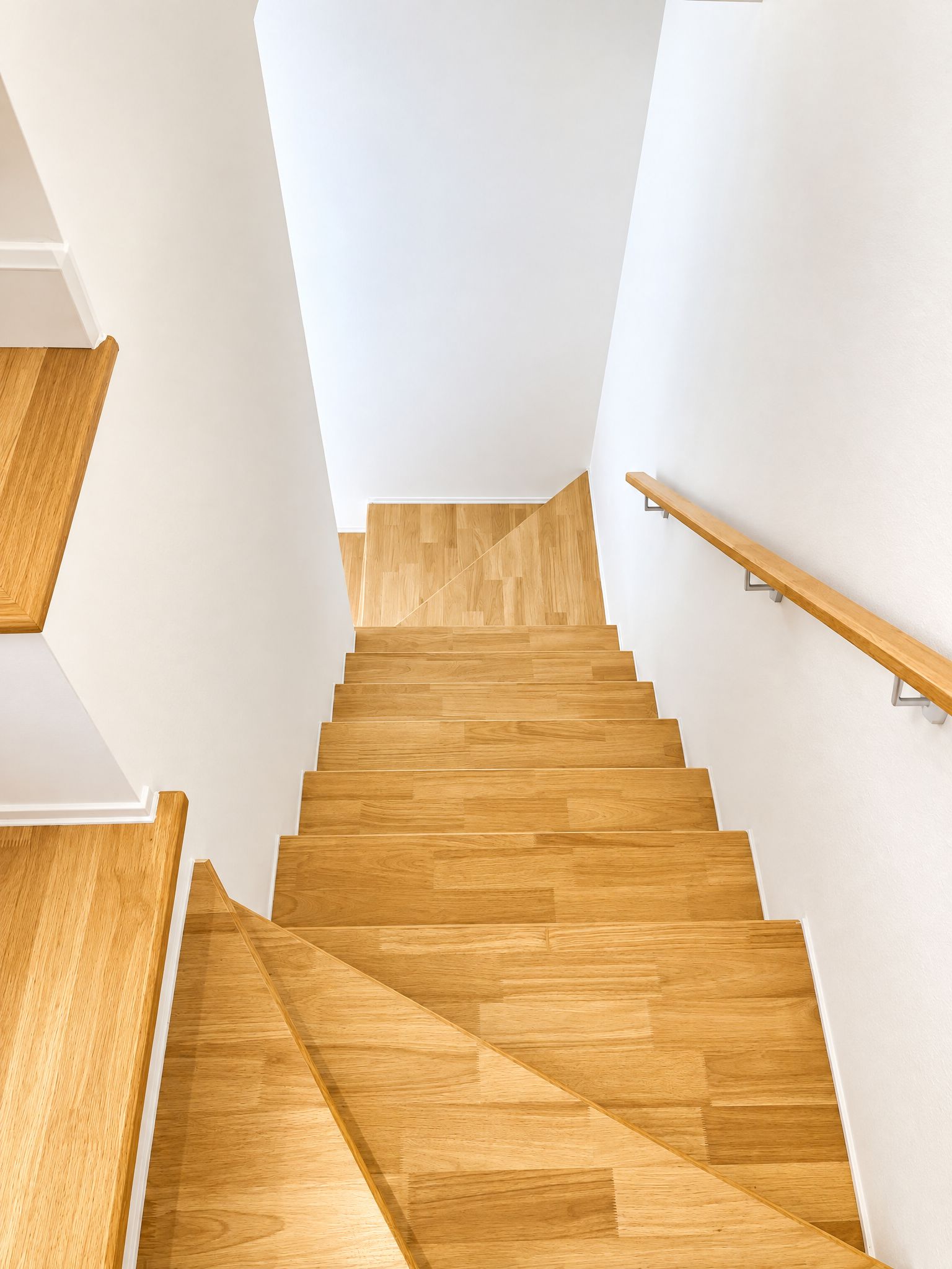 Una escalera de madera con barandilla que conduce a un piso superior.