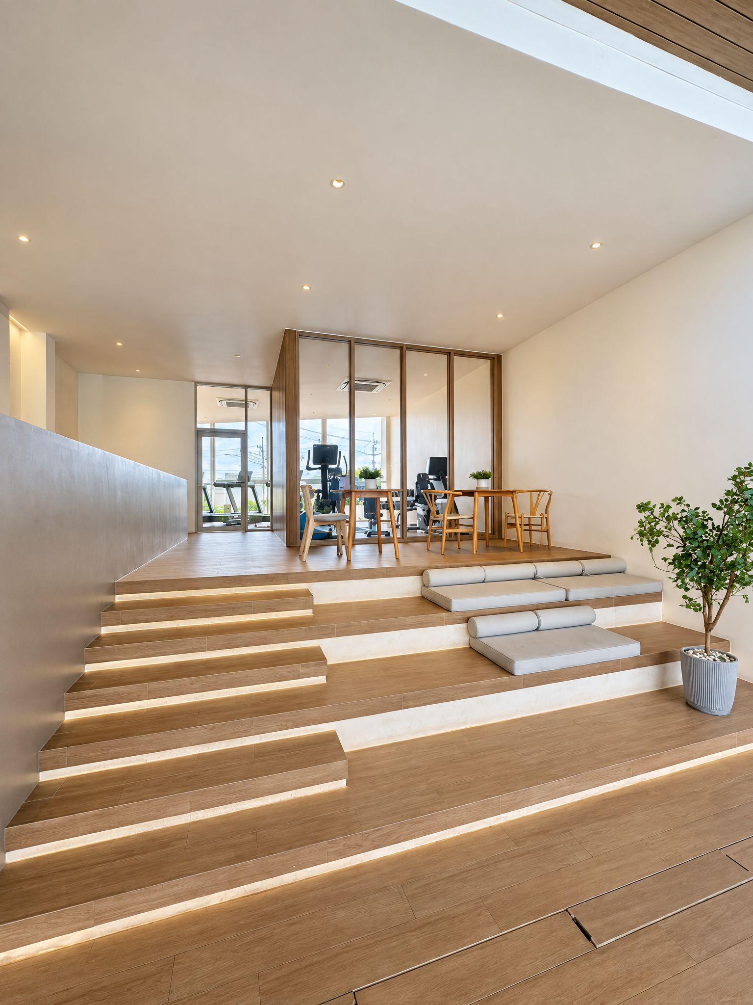 A modern interior with a staircase leading to a living area, a dining table with chairs, and a potted plant.