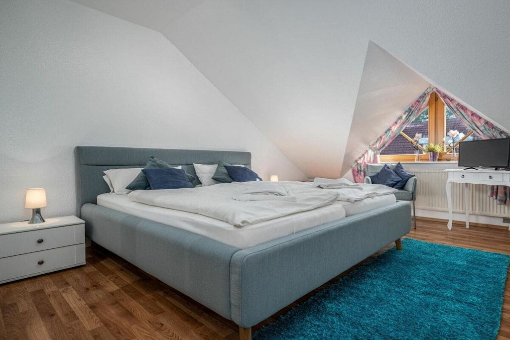 A bedroom with a bed, nightstand, and a desk with a chair.