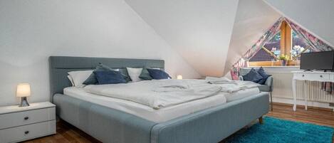 A bedroom with a bed, nightstand, and a desk with a chair.