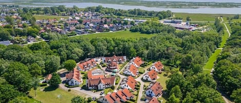 Vista aérea de una zona residencial con casas, una masa de agua extensa y un área boscosa.