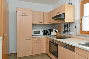 A compact kitchen with wooden cabinets, a microwave, a coffee maker, and a dishwasher. - 5c/T5 Holiday Park "Freesenbruch" (Zingst (Ostseeheilbad))