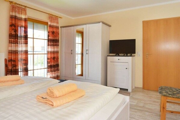 A hotel room with two beds, a wardrobe, a television, and a wooden door. - 5c/T5 Holiday Park "Freesenbruch" (Zingst (Ostseeheilbad))