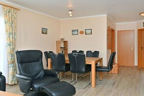 A room with a dining table, chairs, a wooden cabinet, and a door. - 5c/T5 Holiday Park "Freesenbruch" (Zingst (Ostseeheilbad))