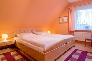 Ein Schlafzimmer mit einem Bett, Nachttischlampen, einem Fenster mit Vorhängen und einer Heizung.