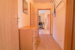 A narrow hallway with wooden doors, a wooden dresser, and a ceiling-mounted rack. - Holiday apartment with 1 bedroom (Zingst (Ostseeheilbad))