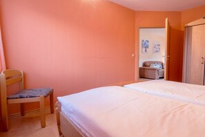 Een slaapkamer met een enkel bed, een houten stoel en een kledingkast.