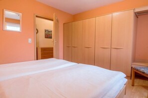 A bedroom with a bed, a wardrobe, and a bench. - Holiday apartment with 1 bedroom (Zingst (Ostseeheilbad))