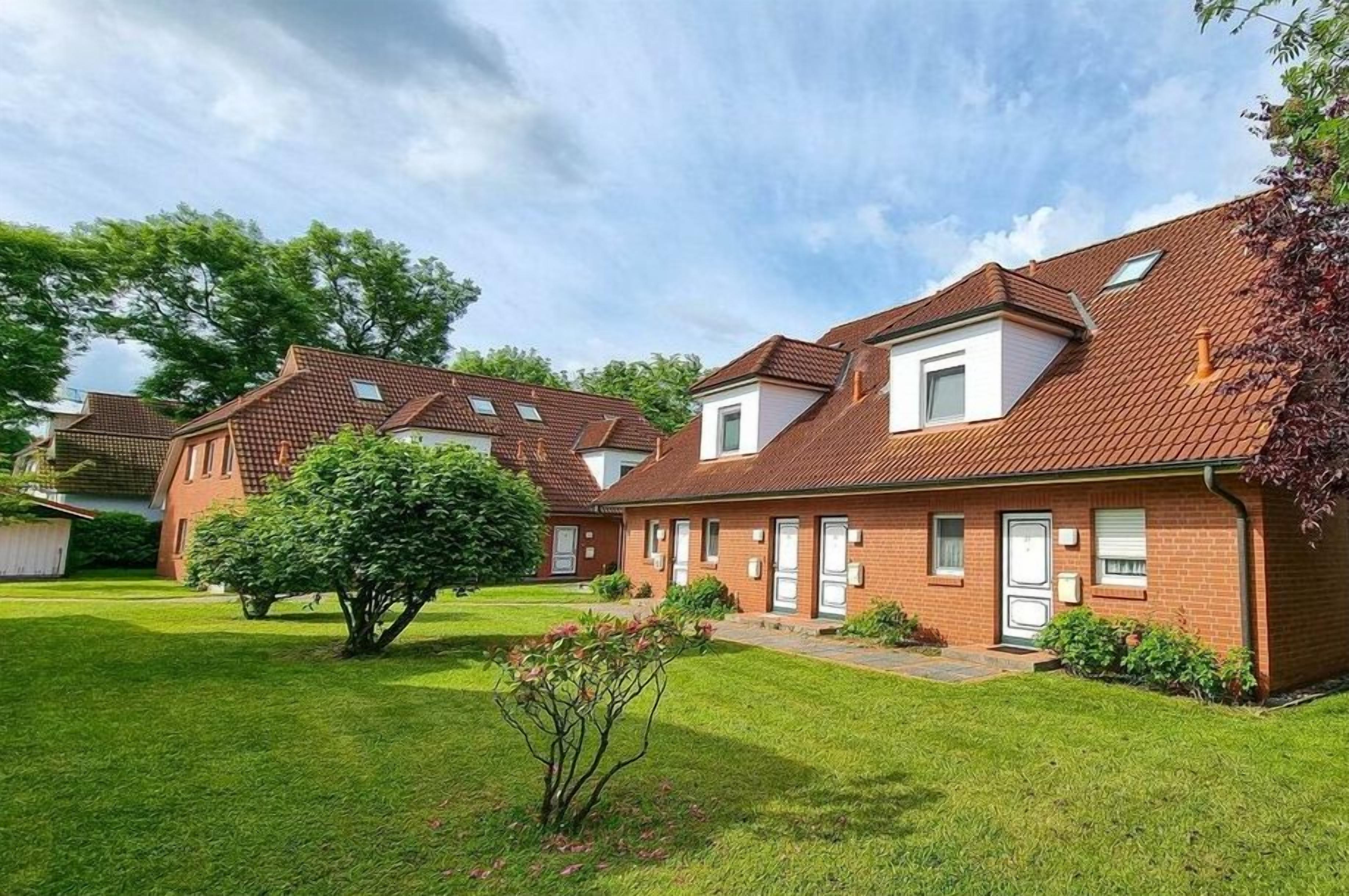A residential building with a red-tiled roof, a brick facade, and a well-maintained lawn.