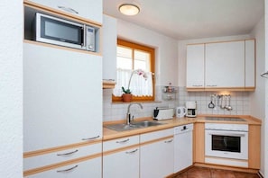 A compact kitchen with white cabinets, a microwave, a toaster, and an oven. - 13a.T4 holiday home park “Freesenbruch” (Zingst (Ostseeheilbad))