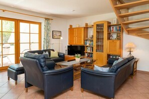 Un salon comprenant un canapé, un téléviseur, une bibliothèque et un escalier.