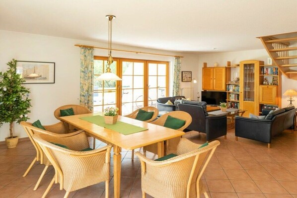 Un salon meublé comprenant un coin repas, un canapé, un téléviseur et une bibliothèque.