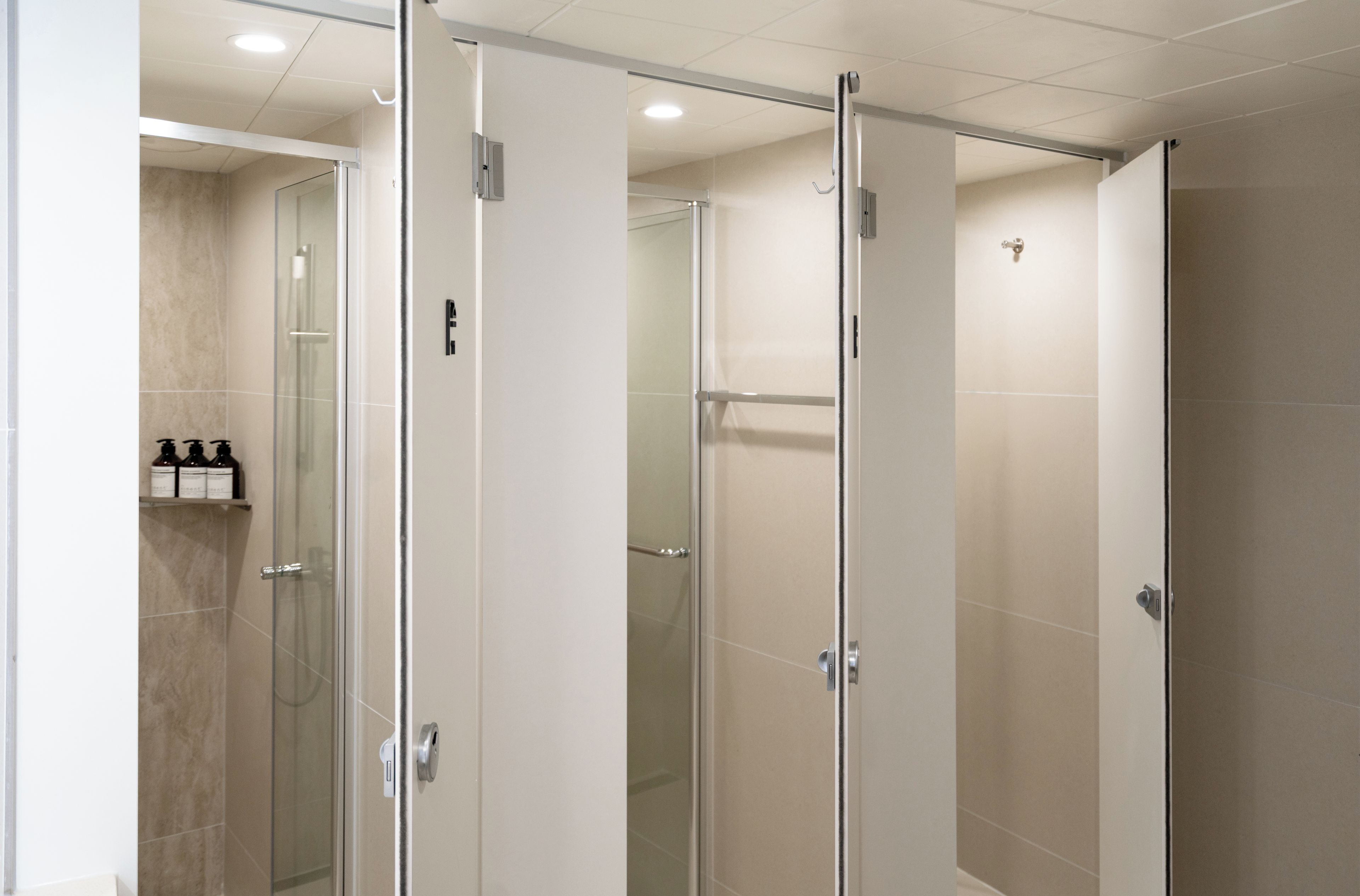 A modern bathroom with glass shower stalls, a toilet, and a sink area.