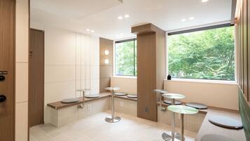 Des toilettes modernes dotées d’un banc, d’une fenêtre donnant sur un espace verdoyant et d’une porte avec une étiquette.