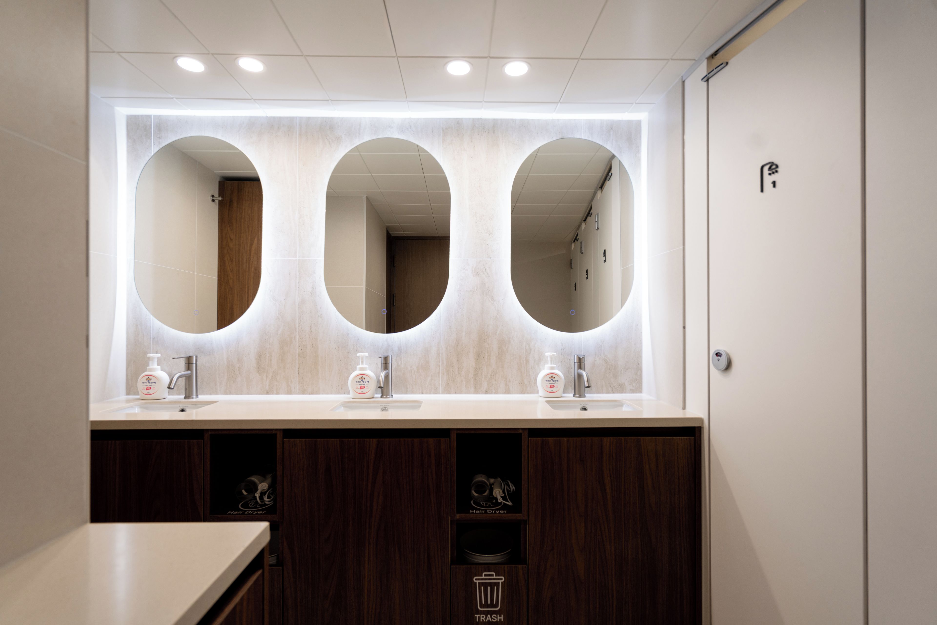 Une salle de bain moderne avec trois miroirs, un lavabo et un sèche-cheveux.