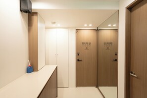 A hotel room with a wooden door, a card reader, and a mirror. - Aka Stay Seoul Station (Seoul)