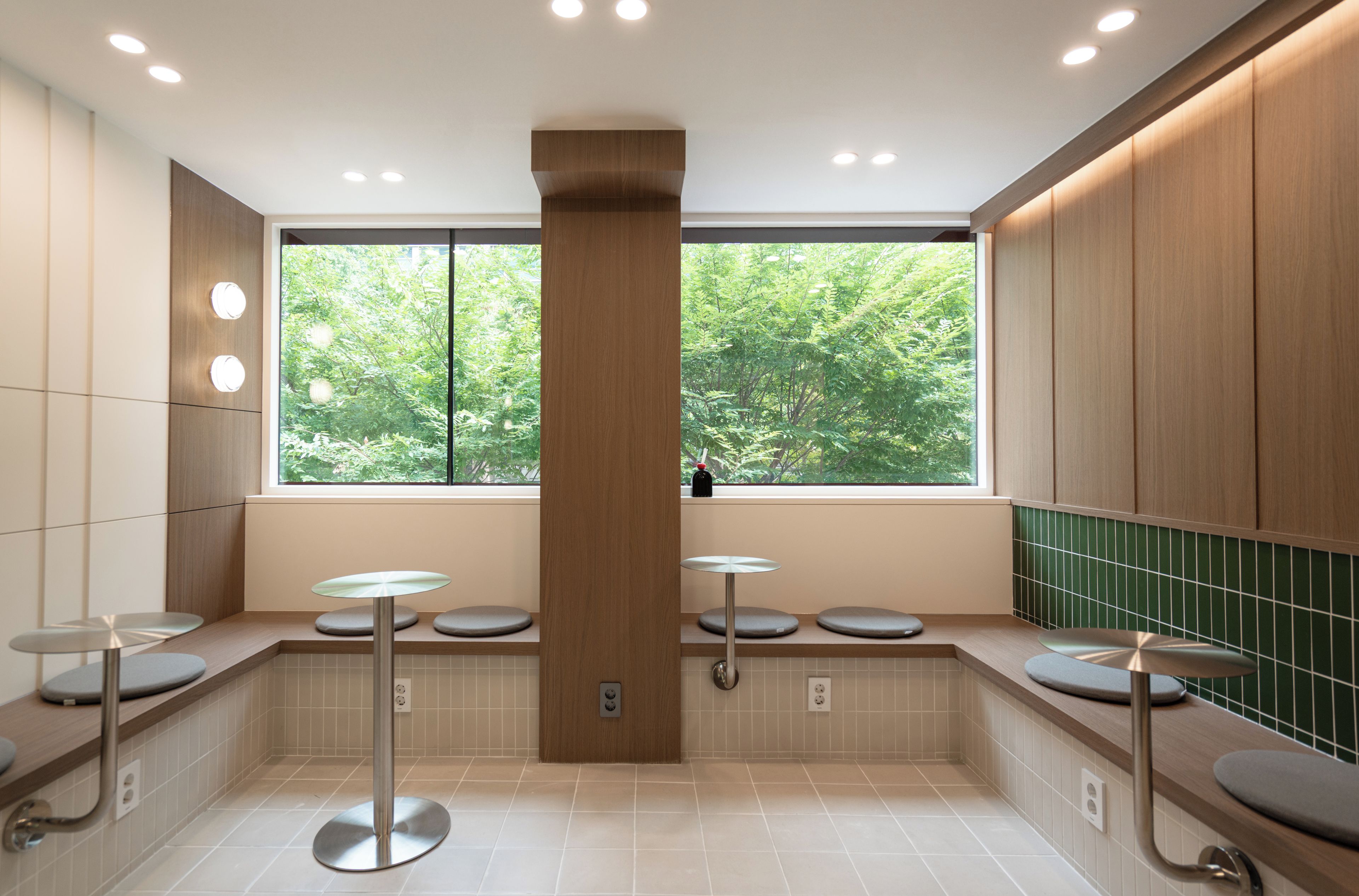 Une salle de bain moderne dotée d’une grande fenêtre, de plusieurs lavabos et d’un pilier central.