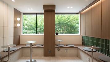 Une salle de bain moderne dotée d’une grande fenêtre, de plusieurs lavabos et d’un pilier central.