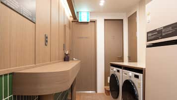 Un baño moderno con paredes de madera, un lavamanos, un espejo y dos lavadoras.