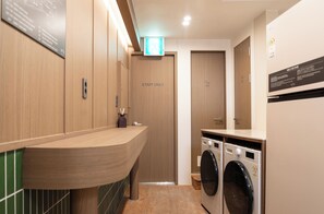 Un baño moderno con paredes de madera, un lavamanos, un espejo y dos lavadoras.