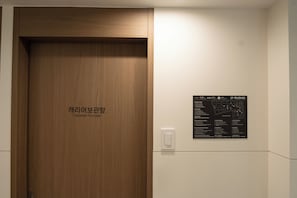 A wooden door labeled 'Luggage Storage' with a wall-mounted emergency information board beside it.