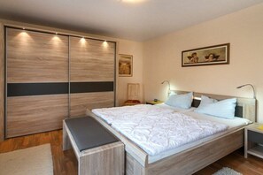 Ein Schlafzimmer mit einem großen Bett, einer Bank, einem Nachttisch und einem Kleiderschrank.
