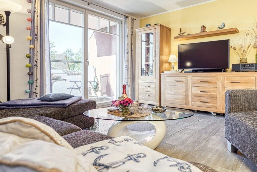 A living room with a sofa, a glass coffee table, a television, and a cabinet.