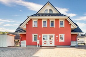 A red house with a gabled roof, a front door with a glass panel, and a small porch area. - Holiday apartment with 1 bedroom (Seeheilbad Zingst)