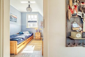 A bedroom with a bed, a nightstand, a lamp, and a wall with nautical decorations. - Holiday apartment with 1 bedroom (Seeheilbad Zingst)