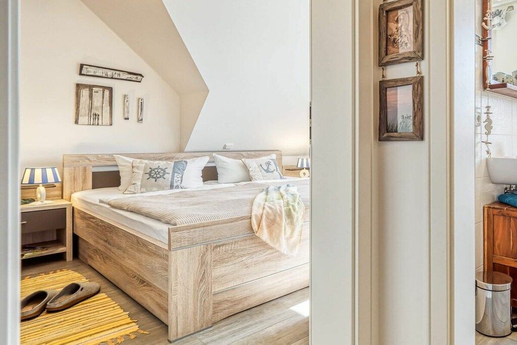 A bedroom with a wooden bed, a nightstand, a lamp, and a wall-mounted shelf.