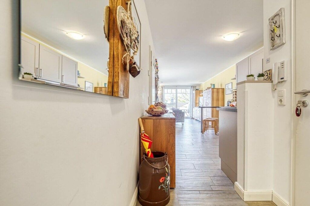 Een hal met een houten kast, een decoratieve spiegel en een houten bankje.
