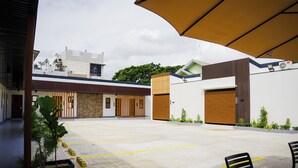 A courtyard with a covered seating area, a building with a modern design, and a clear sky.