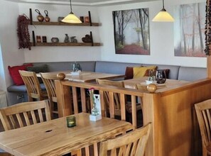 A dining area with wooden tables and chairs, a sofa, and pendant lighting. - 2.3/T4 Holiday Park "Freesenbruch" (Zingst (Ostseeheilbad))