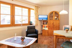A cozy living room with a television, wooden cabinet, and a dining area. - 13b/T4 holiday home park “Freesenbruch” (Zingst (Ostseeheilbad))