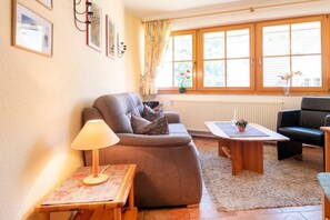 Ein Wohnzimmer mit einer Couch, einem Couchtisch, einer Lampe und einem Fenster mit Vorhängen.