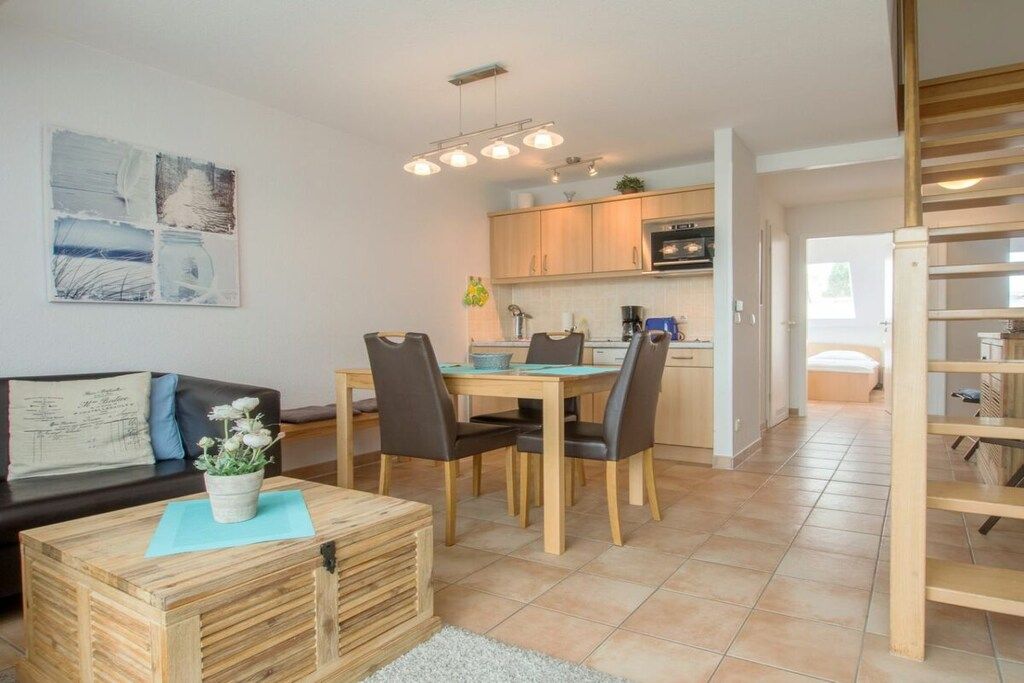 Un espace de vie moderne comprenant un coin repas, une cuisine et un escalier menant à un niveau supérieur.