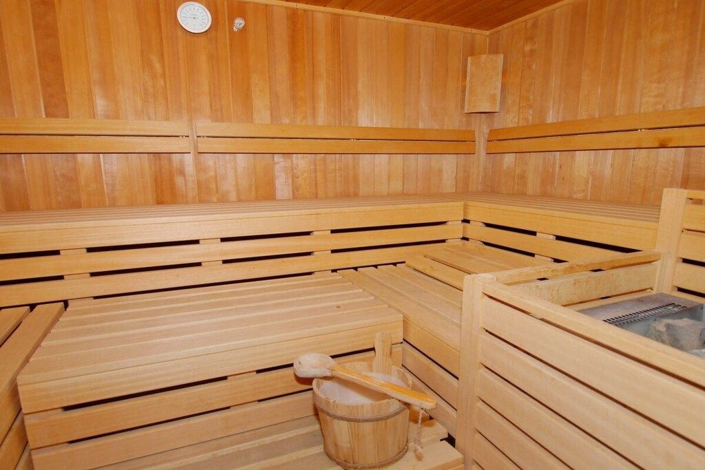 A sauna with wooden benches and a bucket.
