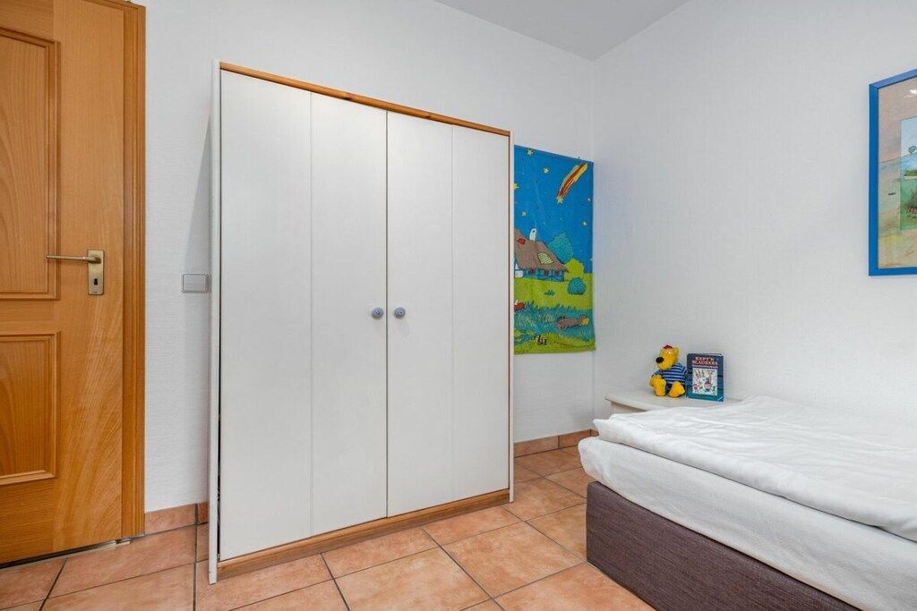Quarto com cama, guarda-roupa e uma parede decorada com um quadro.