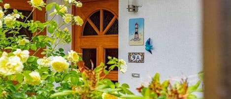 Una puerta de madera con un ventanal, una lámpara fijada a la pared y una pequeña placa con el número '9A'.