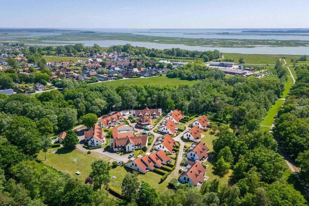 An aerial view of a residential area with houses, a large building, and a body of water in the background.